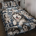 Alaskan Malamute quilt blanket displayed on a bed with snowy mountain scenes, paw prints, and blue plaid accents