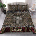 Hunting quilt blanket styled in a bright bedroom with camouflage foliage, antlers, and rustic cross artwork