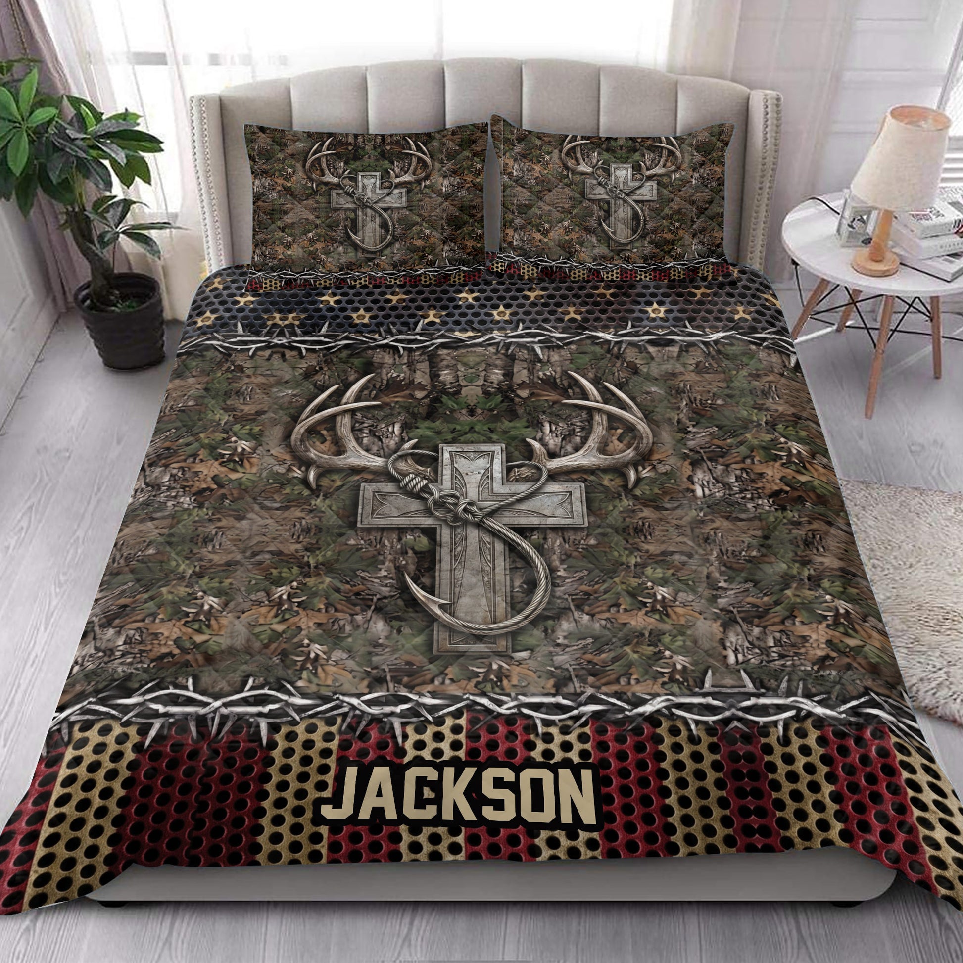 Hunting quilt blanket styled in a bright bedroom with camouflage foliage, antlers, and rustic cross artwork