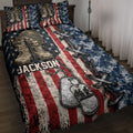 Veteran quilt blanket displayed on a bed with combat boots, helmet, dog tags, crossed rifles and flag artwork