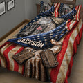 Patriotic veteran quilt blanket spread across a bed with camouflage uniform details, boots, dog tags, and flag stripes