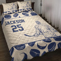 Navy and cream hockey quilt blanket displayed on a bed with player, goalie, stick, and puck artwork