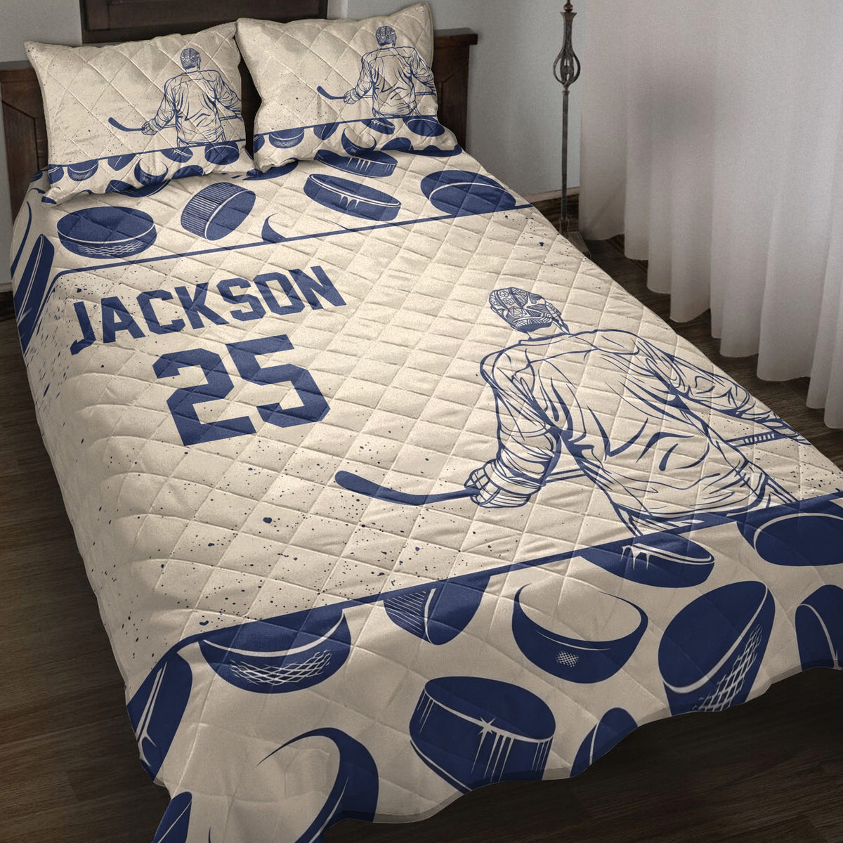 Navy and cream hockey quilt blanket displayed on a bed with player, goalie, stick, and puck artwork