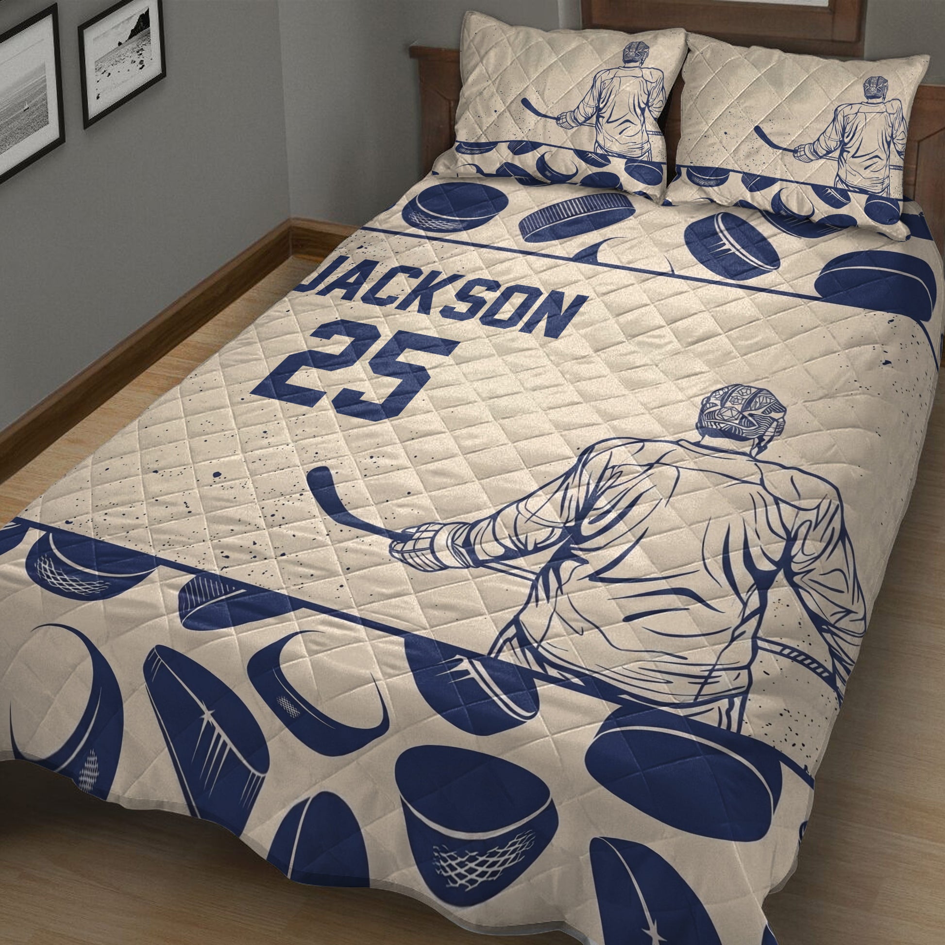 Close bedroom view of a hockey quilt blanket featuring goalie artwork, hockey pucks, and sticks