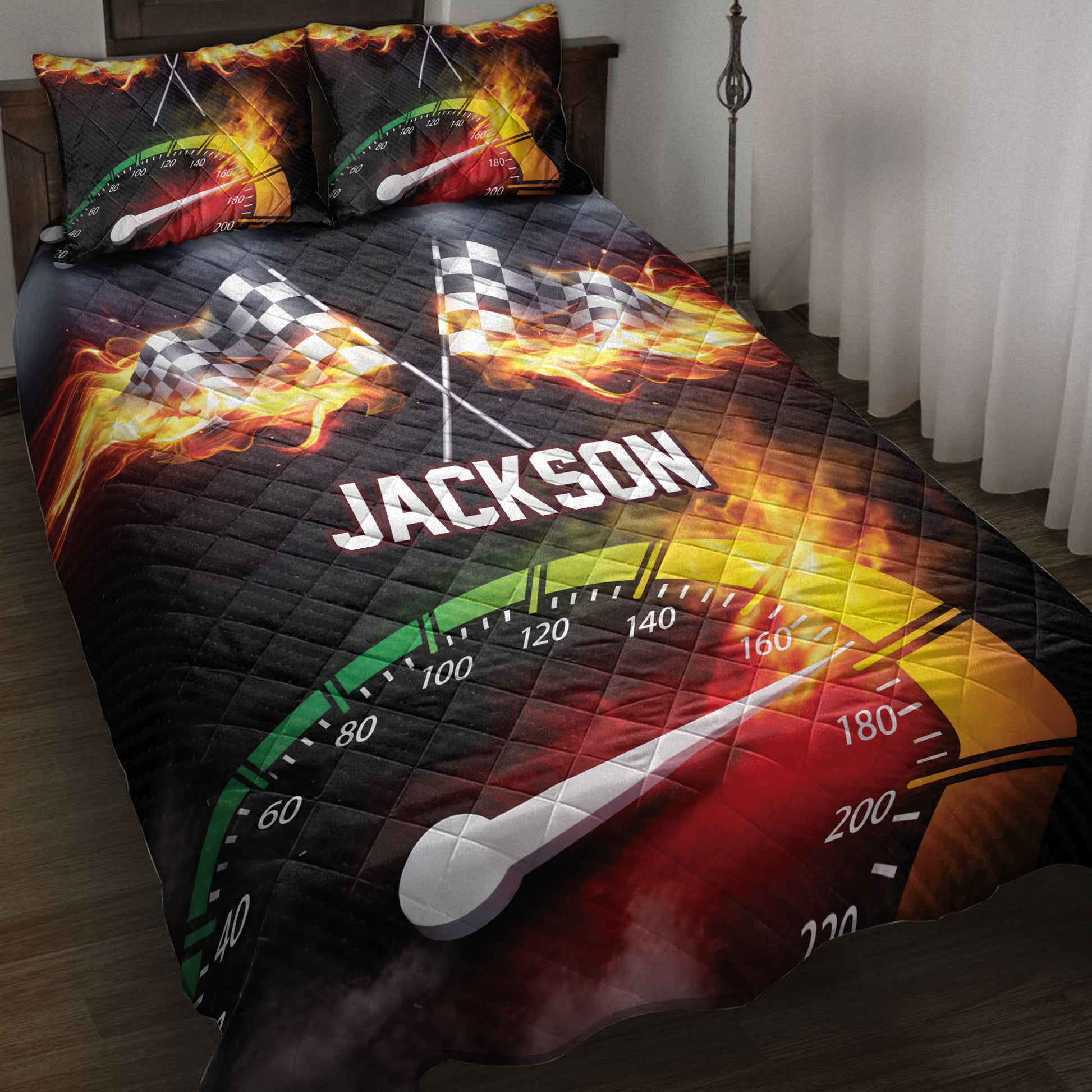 Racing quilt blanket displayed on a bed with flaming checkered flags and speedometer artwork