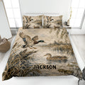 Duck hunting quilt blanket displayed on a bed with mallards, marsh reeds, water, and custom artwork