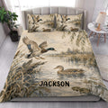 Duck hunting quilt blanket styled in a bedroom with flying mallards, reeds, and wetland scenery