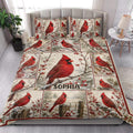 Cardinal quilt blanket styled in a bright bedroom with red birds, berries, pine branches, and winter scenery