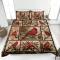 Cardinal quilt blanket displayed on a bed with red birds, berries, pinecones, flowers, and woodland artwork