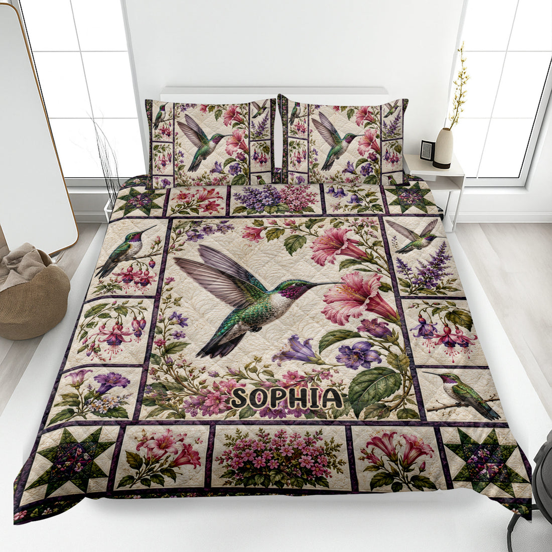 Hummingbird quilt blanket spread across a bed with colorful flowers, botanical panels, and matching pillow designs