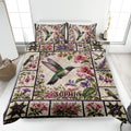 Hummingbird quilt blanket spread across a bed with colorful flowers, botanical panels, and matching pillow designs