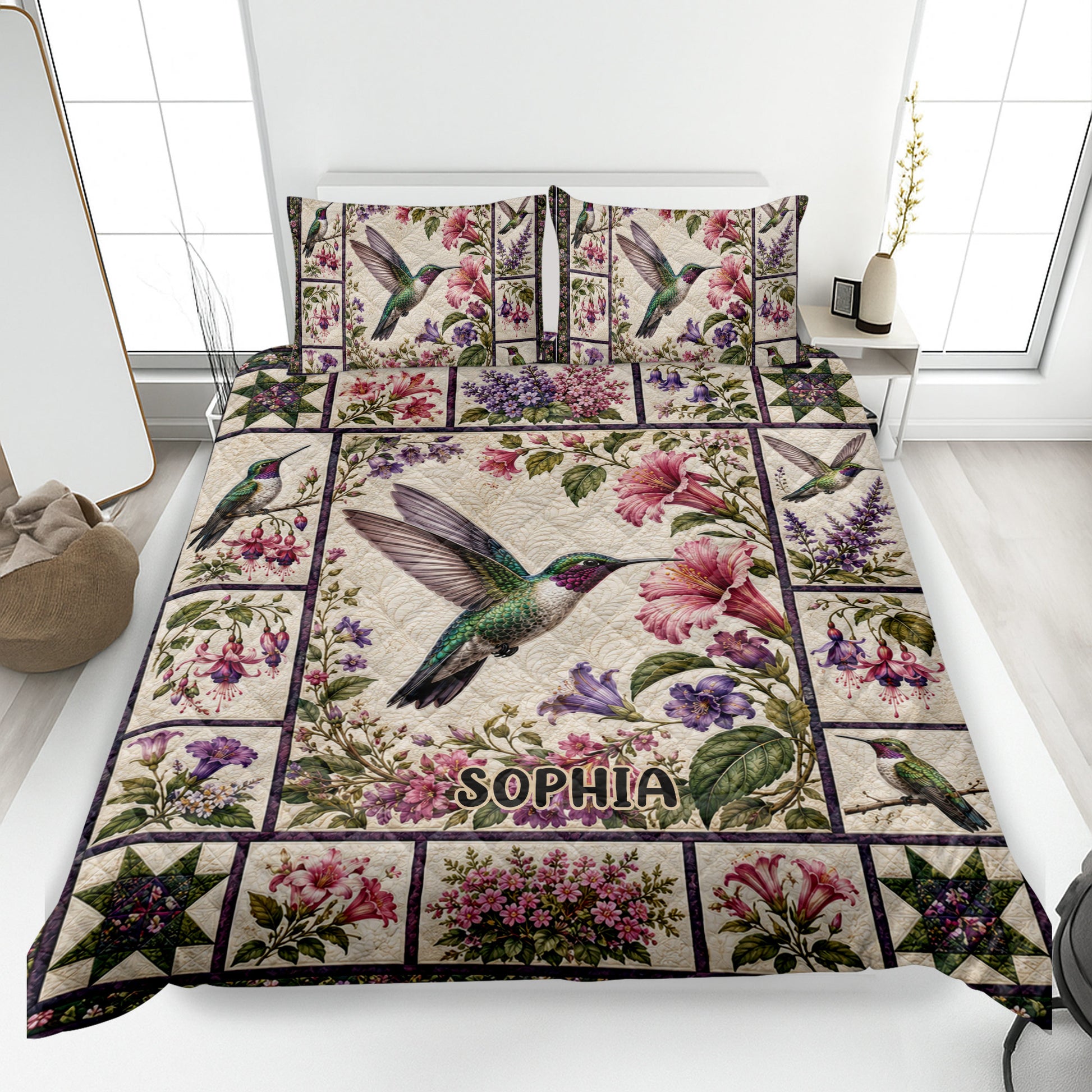Hummingbird quilt blanket spread across a bed with colorful flowers, botanical panels, and matching pillow designs