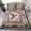 Hummingbird floral quilt blanket styled on a bed in a bright botanical bedroom setting