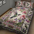Close bedroom view of a hummingbird quilt blanket with vibrant flowers, foliage, and patchwork-style borders