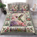 Hummingbird quilt blanket styled on a bright bedroom bed with floral panels and bird artwork