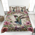 Hummingbird quilt blanket displayed on a bed with colorful flowers and detailed bird artwork