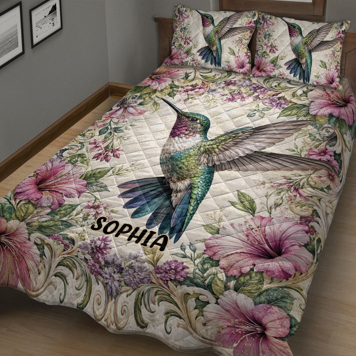 Close bedroom view of a hummingbird quilt blanket with pink flowers and ornate botanical details