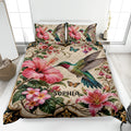 Hummingbird quilt blanket displayed on a bed with hibiscus flowers, butterflies, and botanical artwork