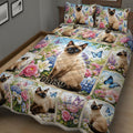 Close bedroom view of a Siamese cat quilt blanket with flowers, butterflies, and cat artwork
