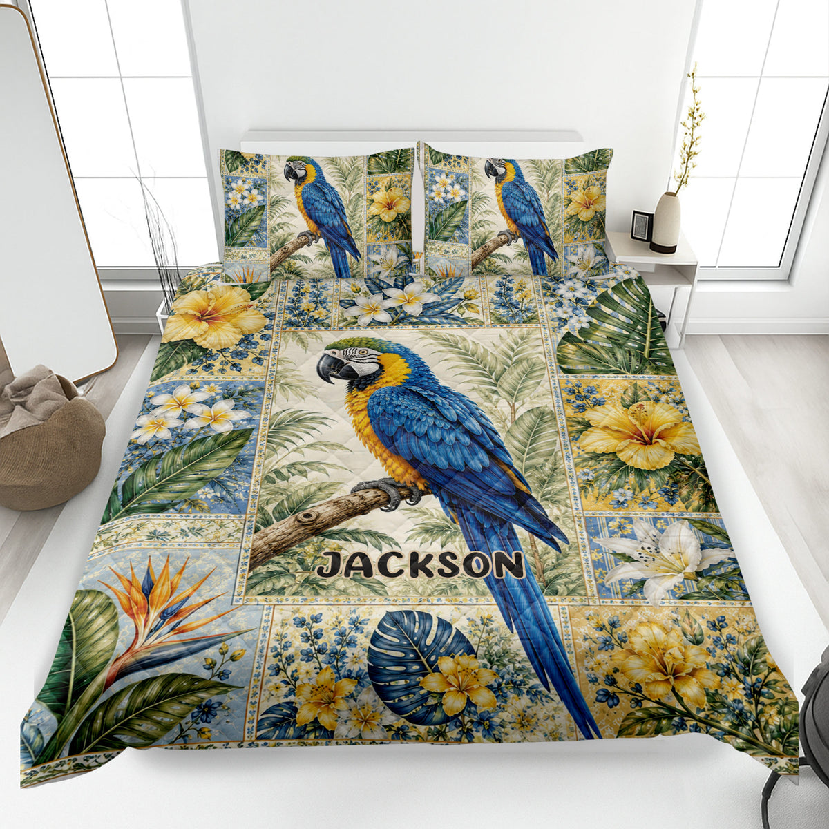 Parrot quilt blanket displayed on a bed with blue macaws, tropical flowers, leafy foliage, and a botanical border
