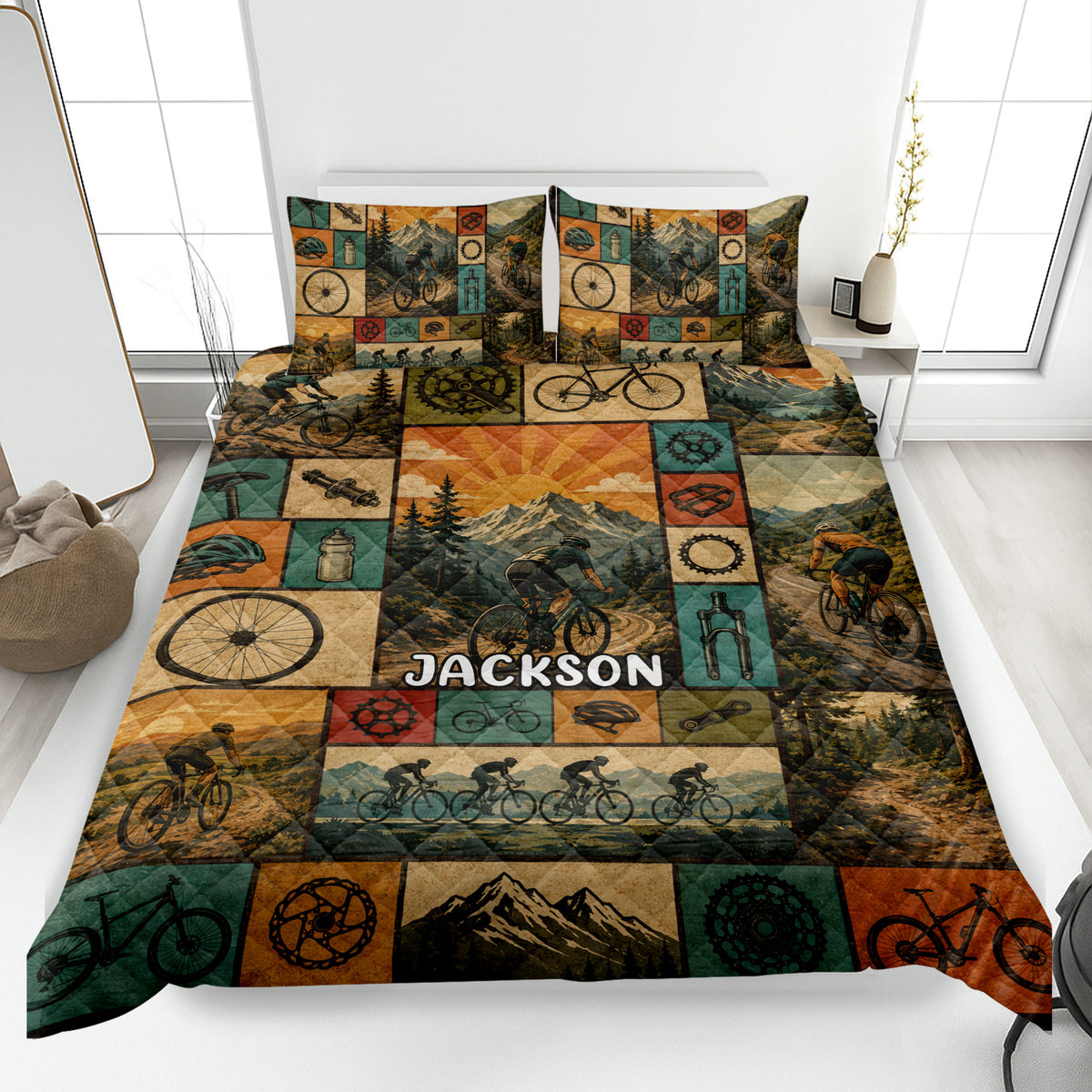 Bicycle quilt blanket displayed on a bed with cyclists, bike parts, mountains, and forest trail artwork