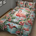 Close bedroom view of a flamingo quilt blanket featuring tropical flowers, palms, and aqua scenery