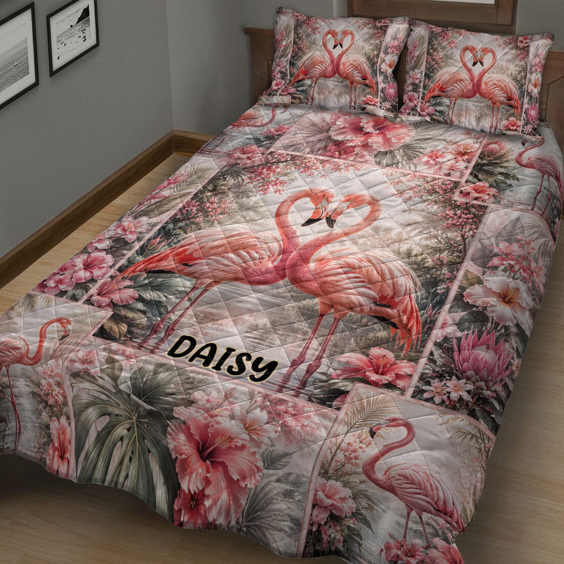 Flamingo quilt bedding displayed across a bed with pink hibiscus flowers and tropical foliage