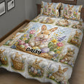 Close bedroom view of a rabbit quilt blanket covered in bunnies, wildflowers, baskets, and pastel eggs