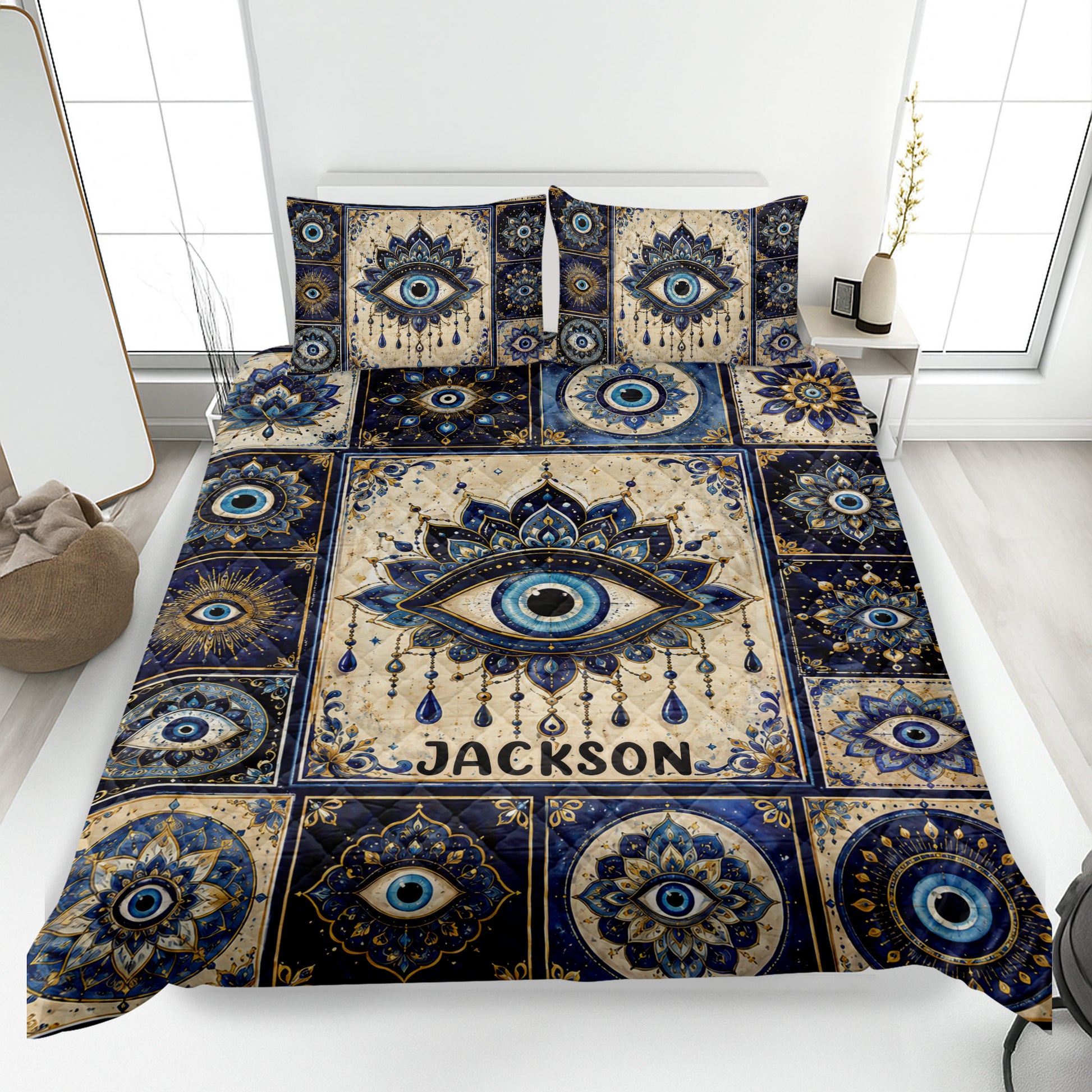Evil Eye quilt blanket spread across a modern bed with ornate blue, gold, and cream eye motifs