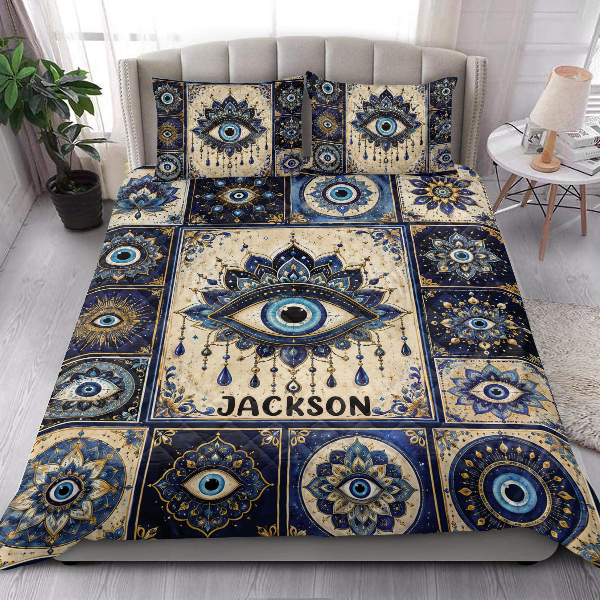 Evil Eye quilt blanket styled on a bedroom bed with bold blue, cream, and gold ornamental artwork