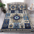 Blue and cream Evil Eye quilt blanket styled across a modern bedroom with matching design details