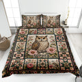 Owl quilt blanket displayed on a bed with floral artwork, birds, patchwork blocks, and a central owl motif