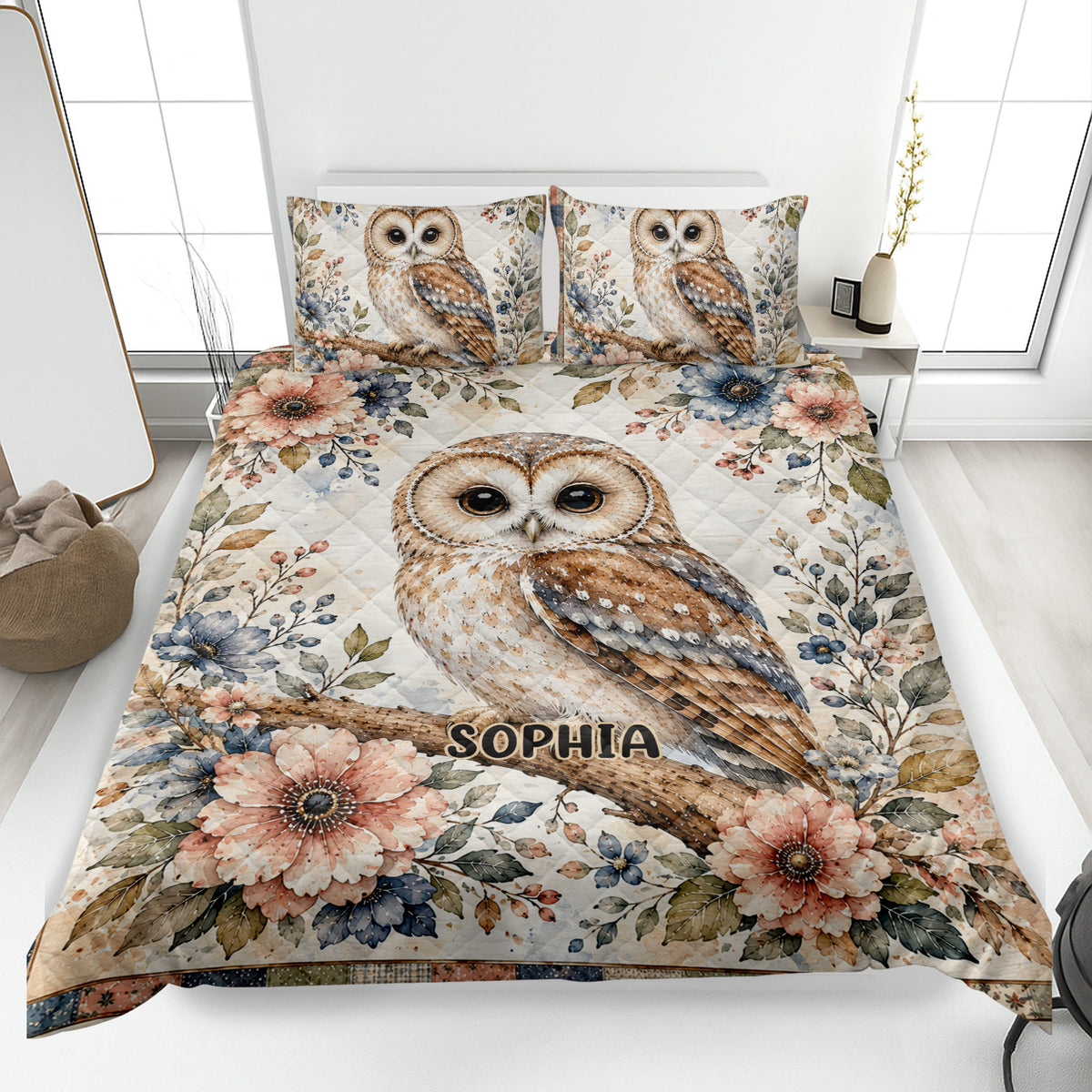 Owl quilt blanket spread across a bed with floral branches, perched owls, and soft botanical colors