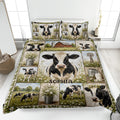 Dairy cow quilt blanket displayed on a bed with farmhouse scenes, wildflowers, barns, milk cans, and windmills