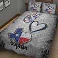 Angled bedroom view of a Texas quilt blanket with large hearts, peace hand artwork, and Lone Star colors
