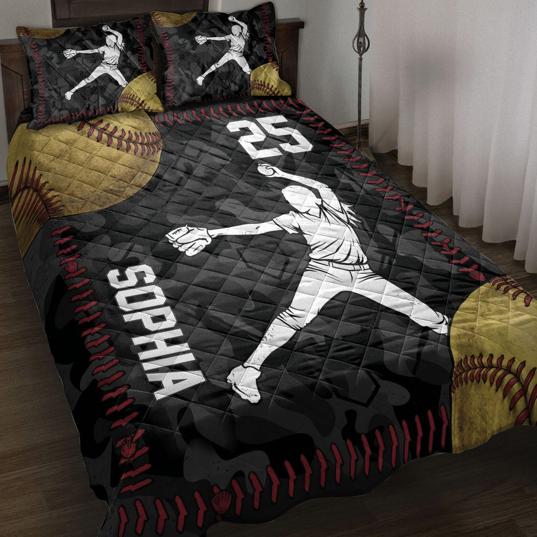 Softball quilt blanket displayed on a bed with pitcher silhouettes, oversized softball artwork, and black, red, and gold details