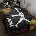 Softball quilt blanket displayed on a bed with pitcher silhouettes, oversized softball artwork, and black, red, and gold details