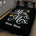 LGBTQ+ pride quilt blanket on a bed with bold white Mrs. and Mrs. artwork and rainbow hearts