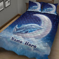 Close bedroom view of a blue dolphin quilt blanket with moon, bubbles, and starry ocean artwork