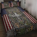 Hunting quilt blanket displayed on a bed with deer antlers, camouflage foliage, and American flag accents