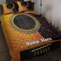 Acoustic guitar quilt blanket in gold, black, and red displayed across a bedroom bed