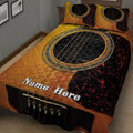 Close bedroom view of a dramatic gold, black, and red acoustic guitar quilt blanket