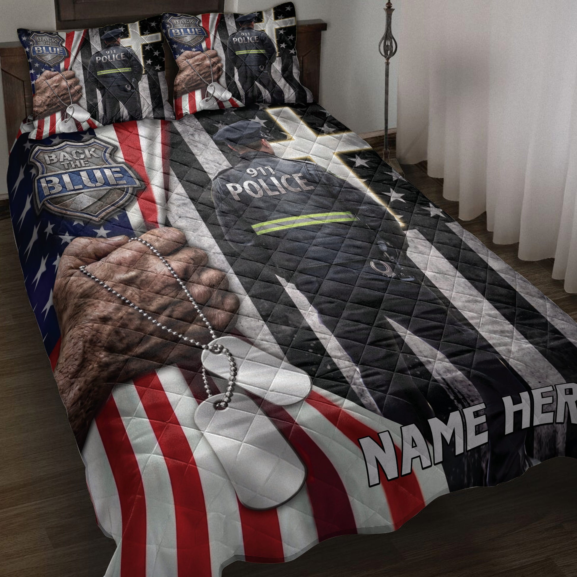 Police quilt blanket displayed on a bed with officer artwork, badge imagery, dog tags, and patriotic red, white, and blue stripes