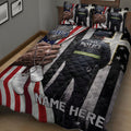 Close bedroom view of a police quilt blanket featuring an officer, badge artwork, dog tags, and red, white, and blue flag stripes