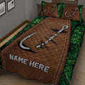 Close view of fishing quilt blanket with large silver hooks, brown quilted center, and green foliage border