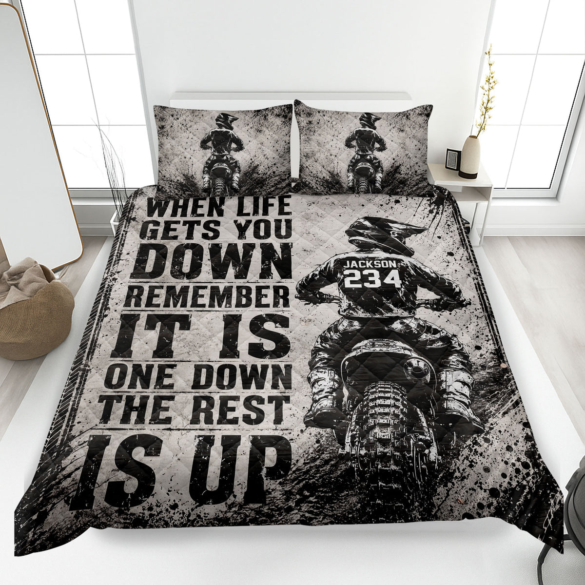Motocross quilt blanket displayed on a bed with dirt bike riders, tire tracks, and bold black and white racing artwork