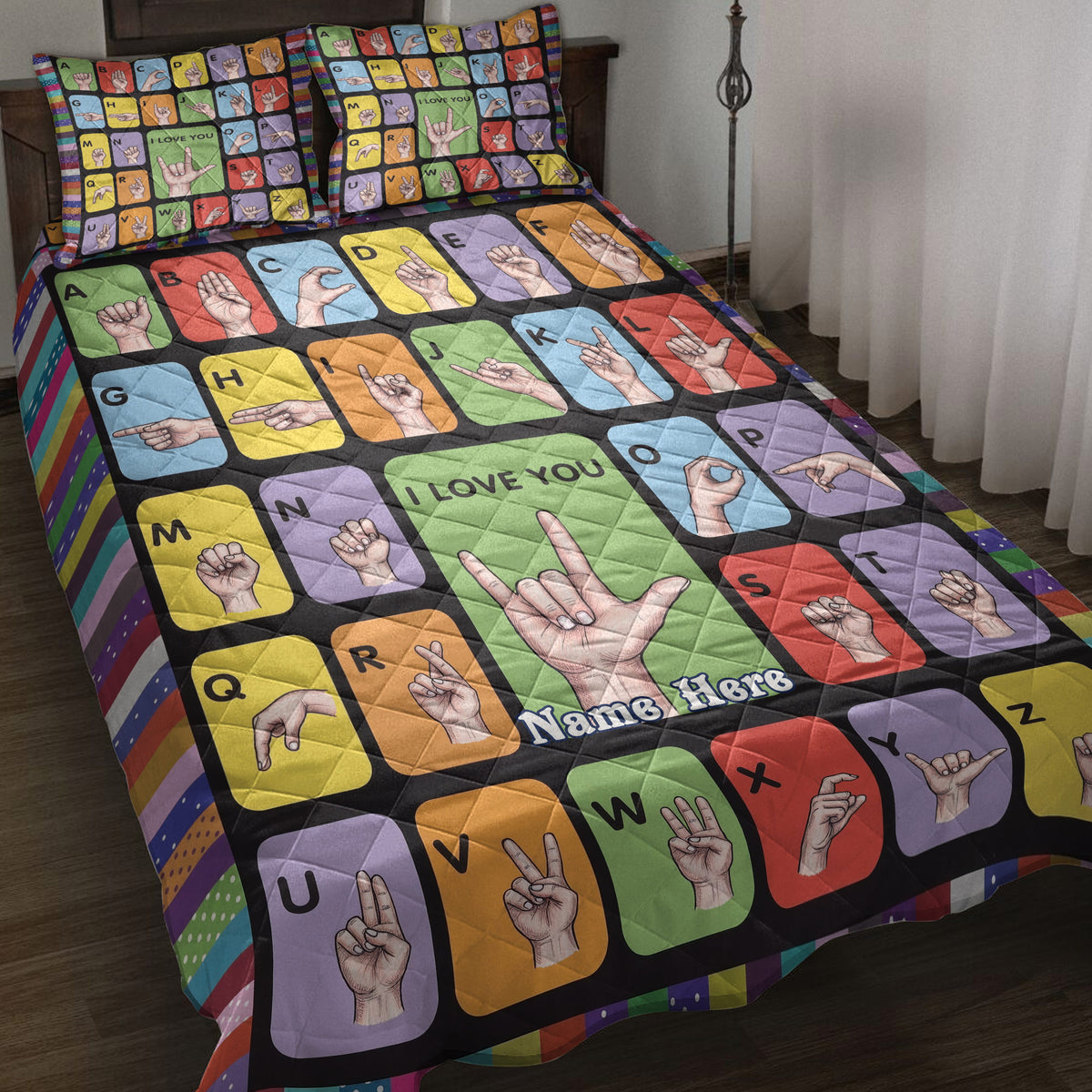 Colorful sign language alphabet quilt blanket displayed on a bed with matching hand sign artwork