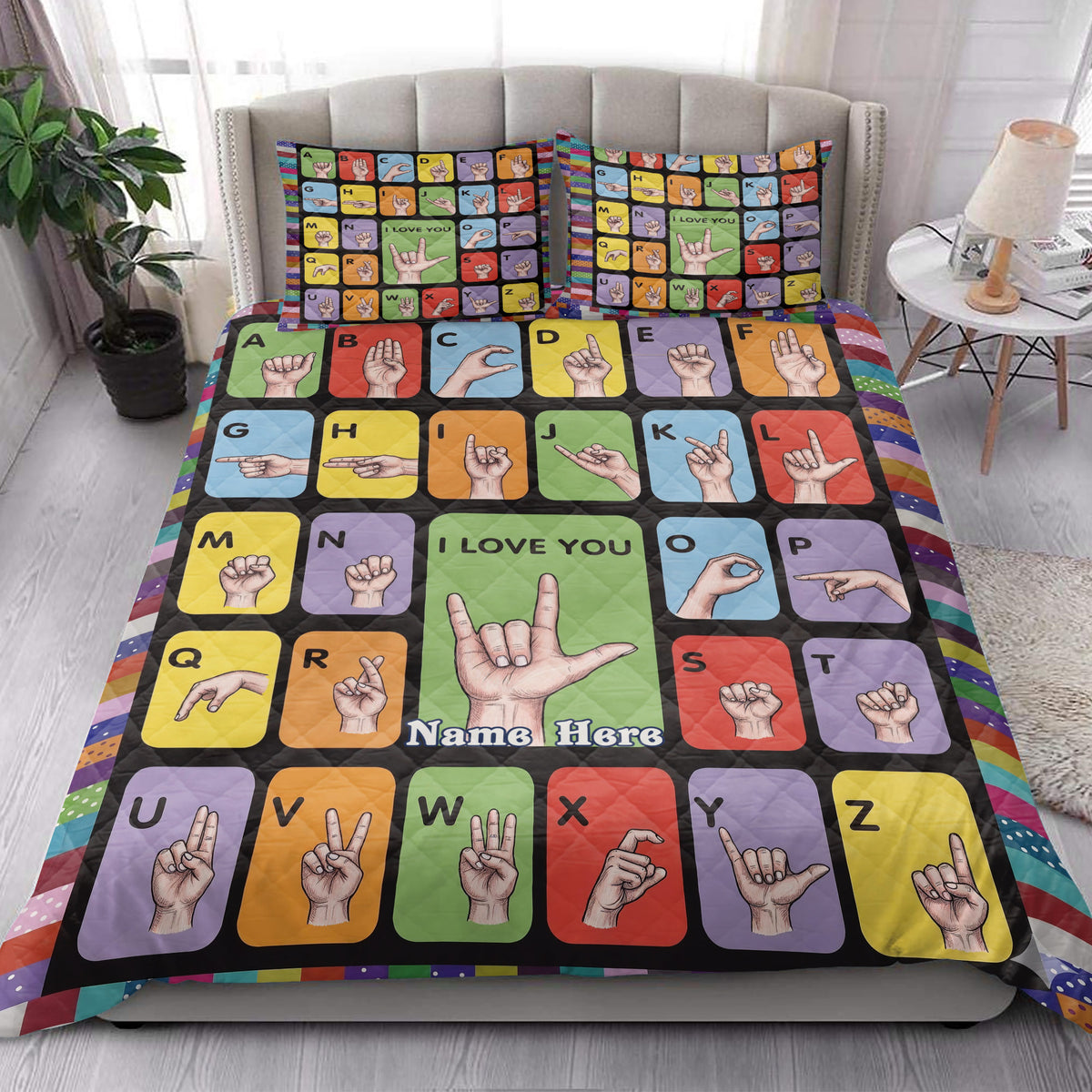 Sign language alphabet quilt blanket styled on a bedroom bed with colorful hand sign blocks