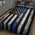 Black and white police quilt blanket with blue stripe and star pattern presented on a bedroom bed
