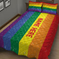 Colorful rainbow Pride quilt blanket and striped pillows displayed in a cozy bedroom